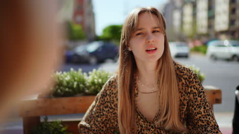 young woman in a leopard print shirt at an outdoor cafe