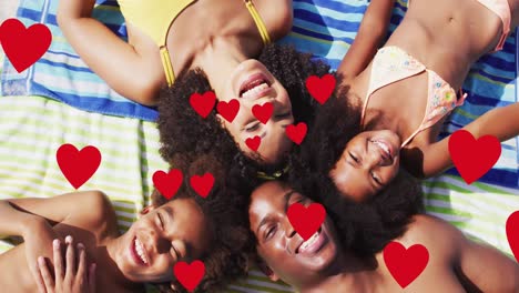 Animación-De-Corazones-Rojos-Sobre-Una-Familia-Afroamericana-Sonriente-De-Vacaciones-Tumbada-En-Toallas-De-Playa