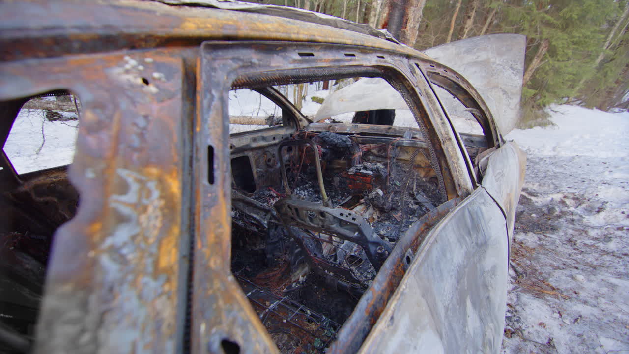 Crashed and burned out car wreck on snowy roadside, reckless driving concept