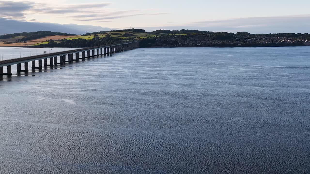 Smooth aerial pan reveals Tay Road Bridge spanning river toward Dundee, Scotland, under soft daylight