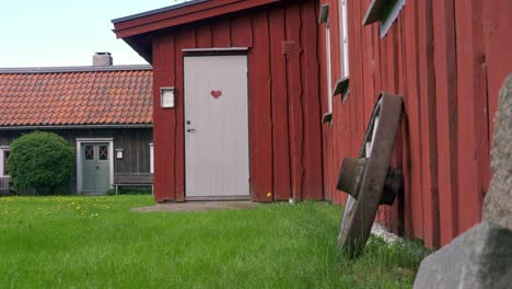 red farmhouse buiding with horse cart wheel against wall with pan shot right to left in sweden