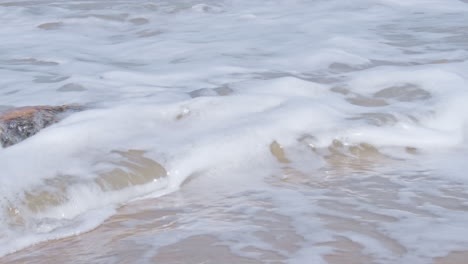 Schaumige-Wellen-Brechen-An-Einem-Sonnigen-Sommerstrand-In-Alte-Verfaulte-Holzstämme