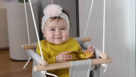 Cute-baby-sitting-doorway-swing-and-playing-with-silicon-flower-toy-smiling