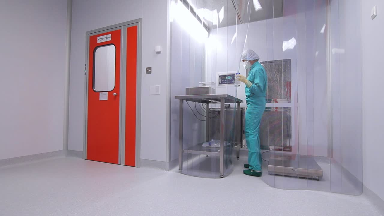 trabajadora en uniforme que trabaja en una sala estéril en una fábrica farmacéutica