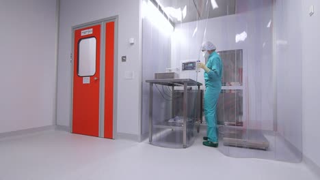 female worker in uniform working in sterile room at pharmaceutical factory