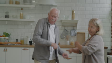 una pareja de mayores bailando en la cocina.