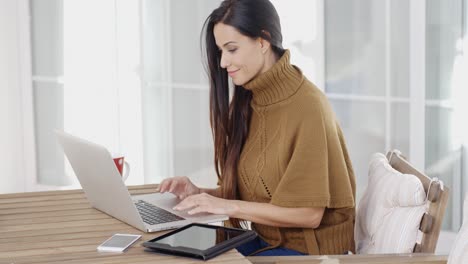 mujer atractiva sentada escribiendo en una computadora portátil