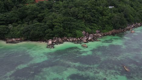 aerial high angle coral reef sea scenic coastline covered in green tropical palm tree jungle vegetation in la digue island, seychelles archipelago indian ocean
