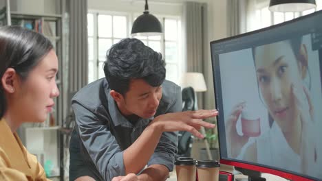 Asian Male Art Director Consults Designer Colleague, They Work On A Portrait In Photo Editing Software. They Work In A Cool Office Loft