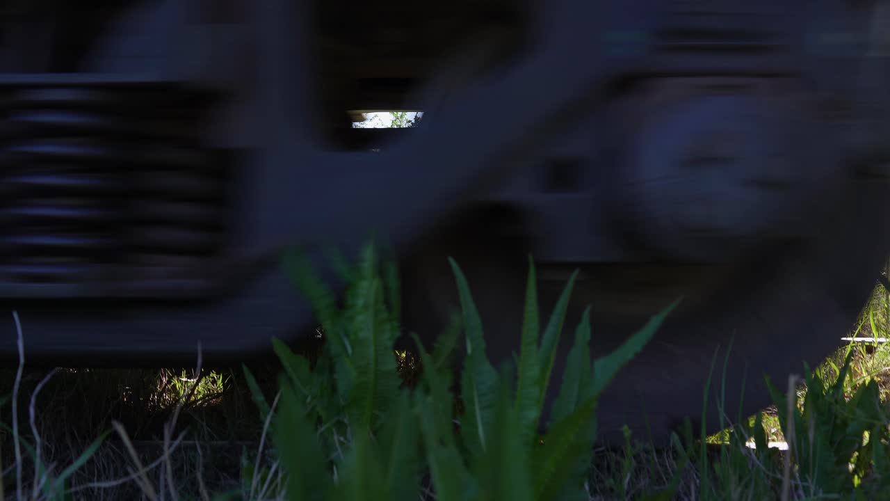 Closeup of a train's wheels over a railway on a rural area.