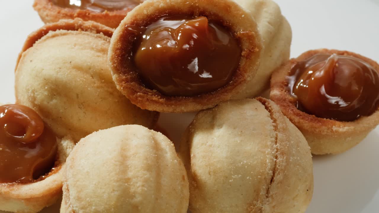 집에서 만든 견과류 모양의 쿠키와 여진 응축 우유가 회색 테이블에 평평하게 놓여 있습니다. 고품질의 4k 영상