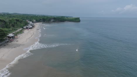 Aerial-drone-flying-over-tropical-Balangan-Beach-in-Uluwatu-Bali-Indonesia-with-polluted-muddy-water-and-floating-trash-and-debris