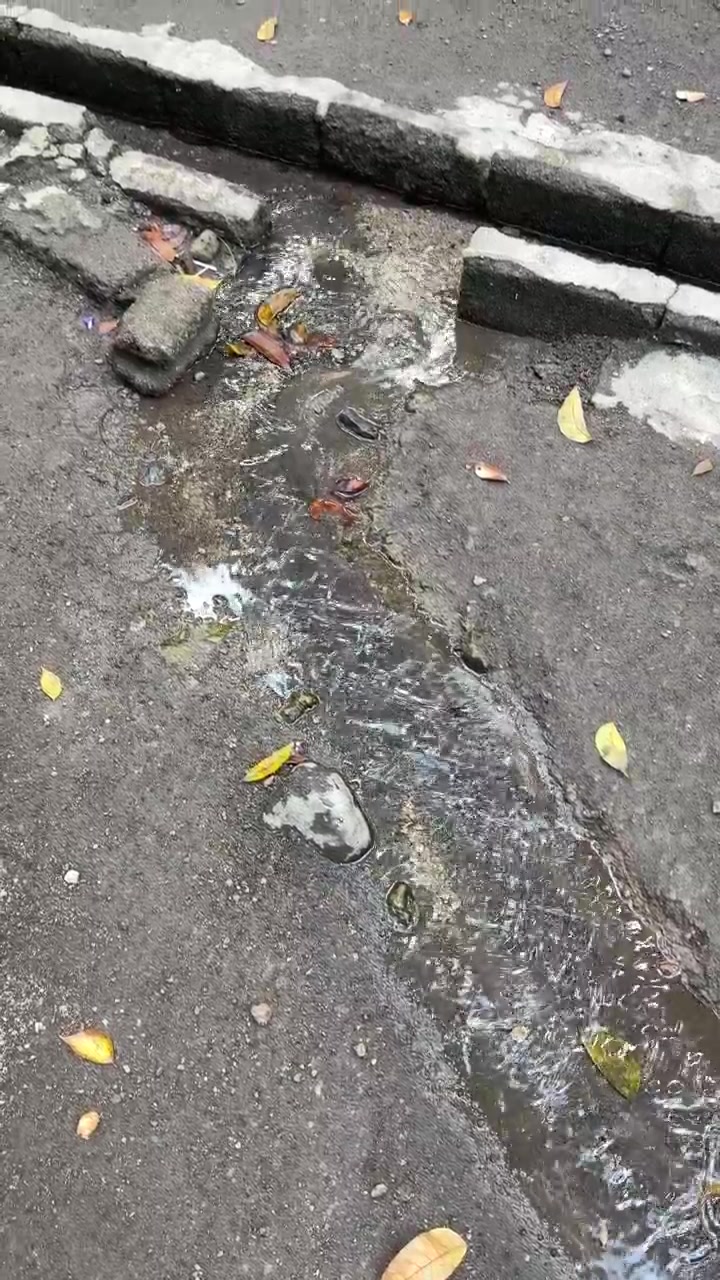 Wasser fließt durch eine Betonrinne auf einer Stadtstraße