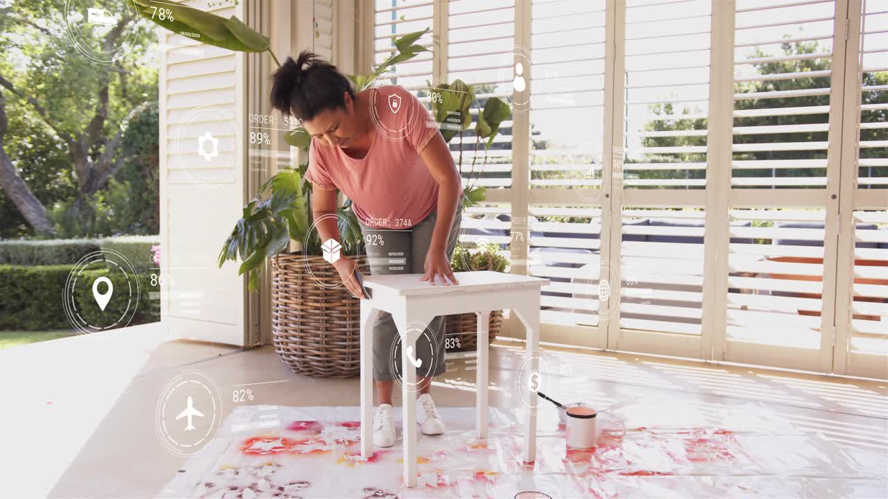 Woman stabilizing table and applying controlled brush strokes for home refurbishment on drop cloth