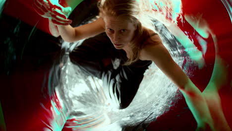 woman performing inside distorted mirrored space filled with colorful light