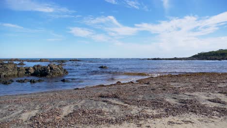 Ein-Zeitraffer-Der-Ankommenden-Flut-An-Einem-Felsigen-Strand-Mit-Blauem-Himmel-An-Einem-Südlichen-Ozeanstrand