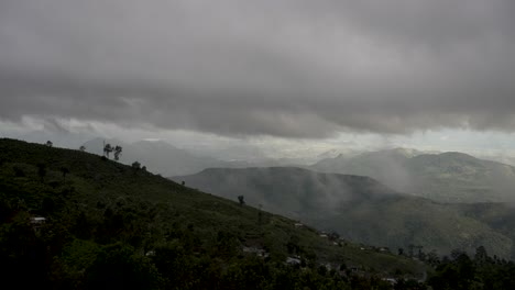 nubes oscuras cubriendo el cielo sobre una cadena de montañas tropicales verdes, creando una atmósfera temperamental y dramática