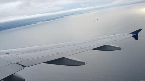 Passagieransicht-Des-Flugzeugflügels,-Der-über-Dem-Meer-Fliegt,-Bewölkter-Tag