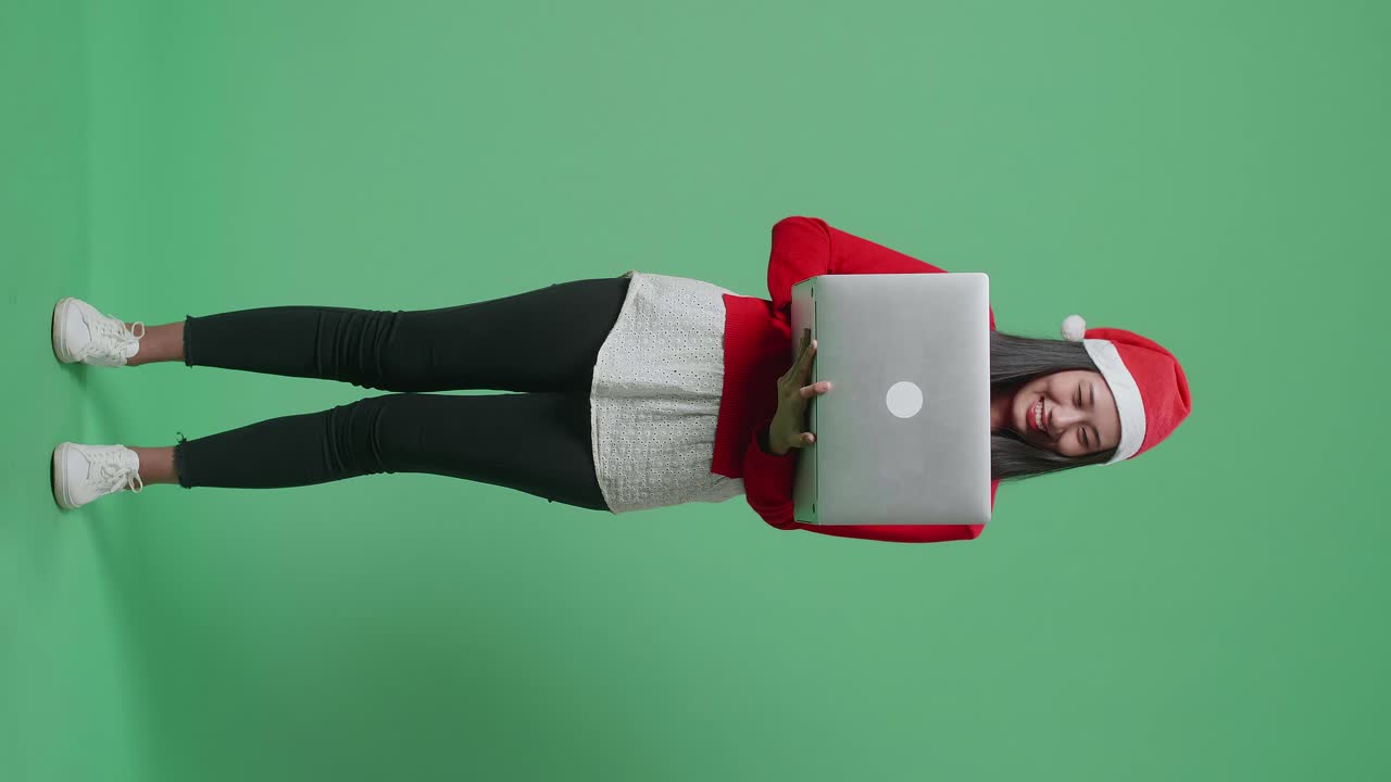 una mujer con una computadora portátil con un sombrero de papá noel