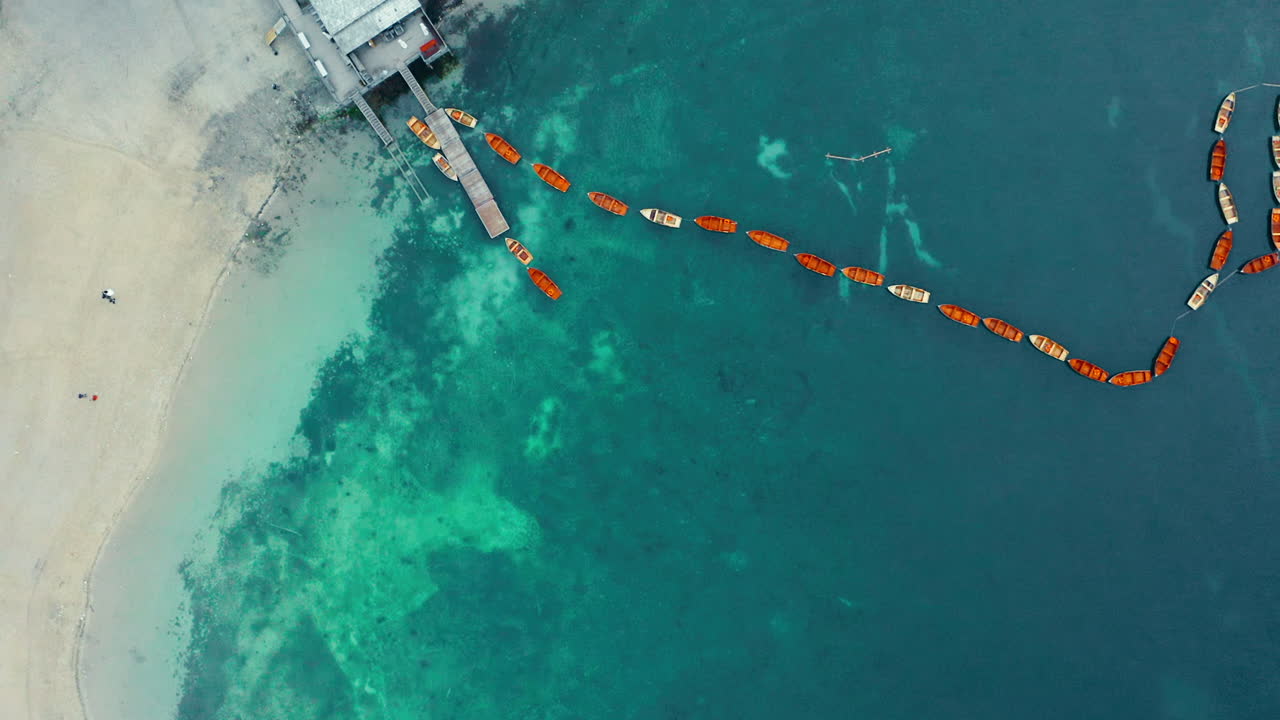 라고 디 브라이에스(lago di braies)의 깨끗한 해안에 정박해 있는 붉은 나무 노젓는 배의 나선형 공중 신의 전망, 공중