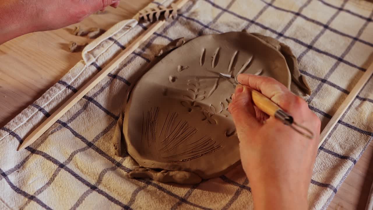 스튜디오 에서 도자기 - 여자 는 점토 조각 에 패턴 을 만든다