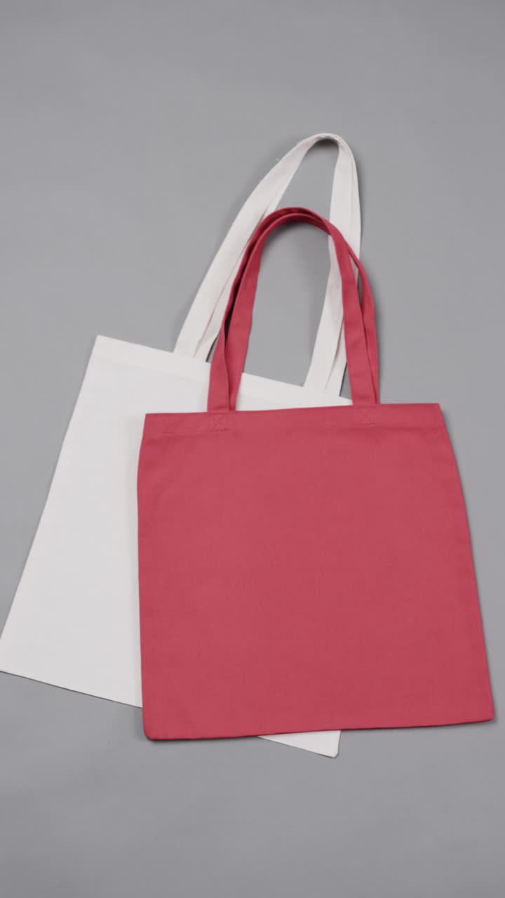 Vertical video of high angle view of red and white canvas bags with copy space on white background