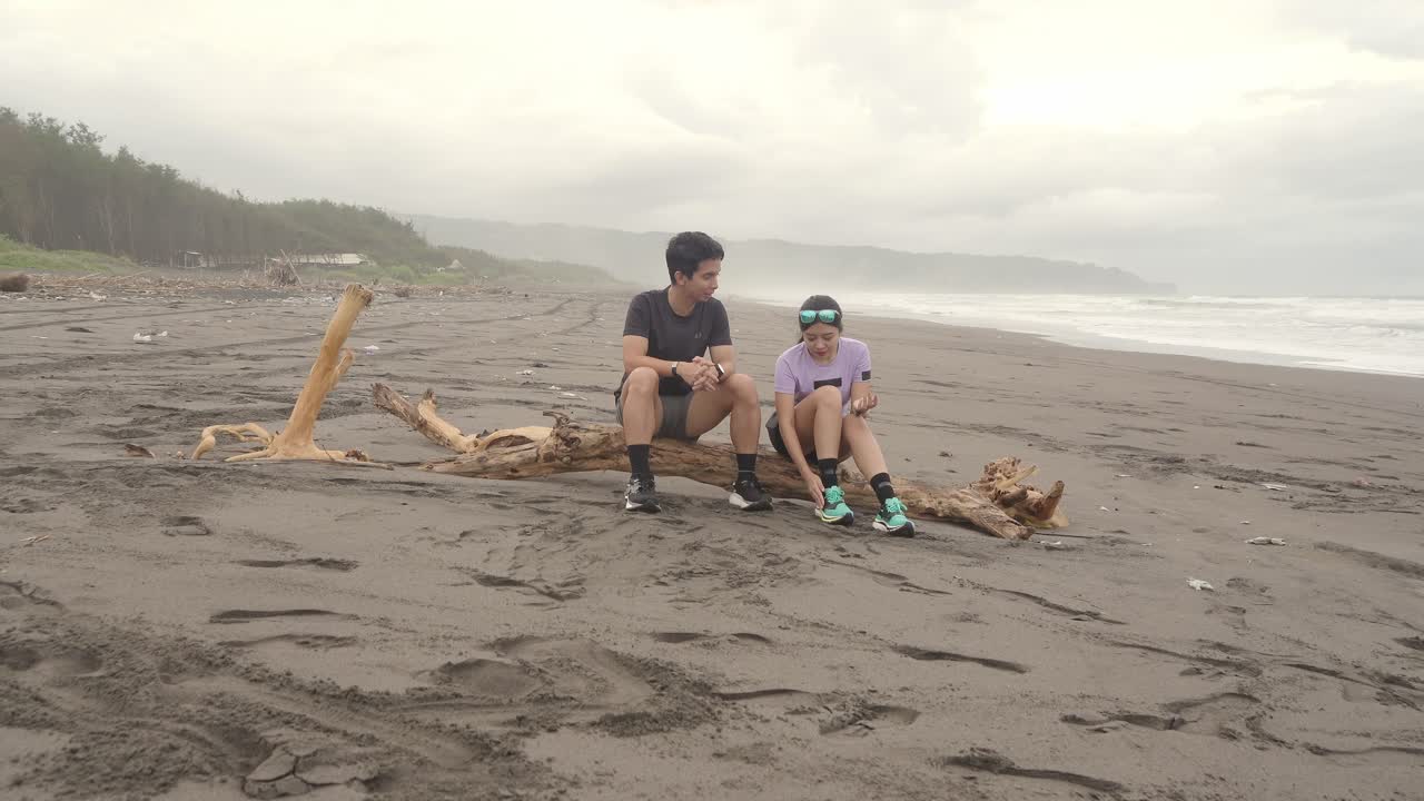 Couple Sitting on Driftwood at the Beach