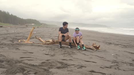 couple sitting on driftwood at the beach