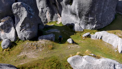 Tourist-walking-on-grass-between-gigantic-rock-formation-of-Castle-Hill-during-sunlight