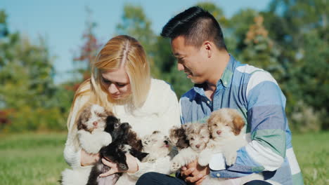 Young-Couple-Holding-Litter-of-Puppies