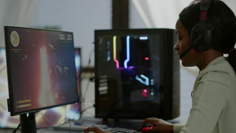 furiosa mujer africana jugadora con auriculares perdiendo un videojuego de disparos espaciales