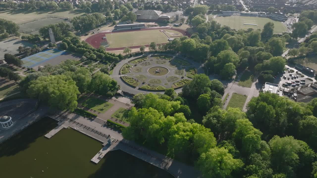 Italian style gardens, lake and running track with slow reveal of wider suburban area. Stanley Park, Blackpool, Lancashire, UK.