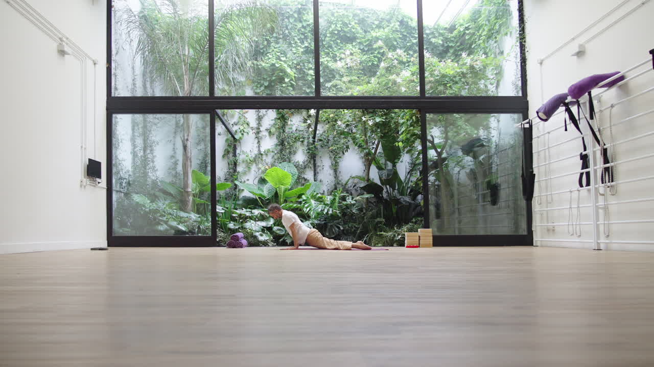 Man Practicing Yoga Cobra Pose in a Serene Studio with Garden View