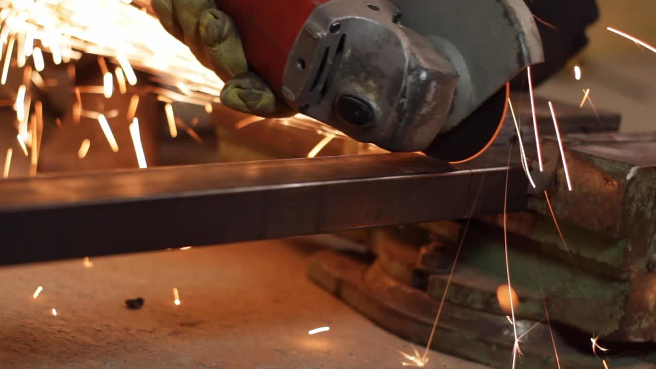 Disc grinder used my worker to cut steel pipe on vise creates sparks