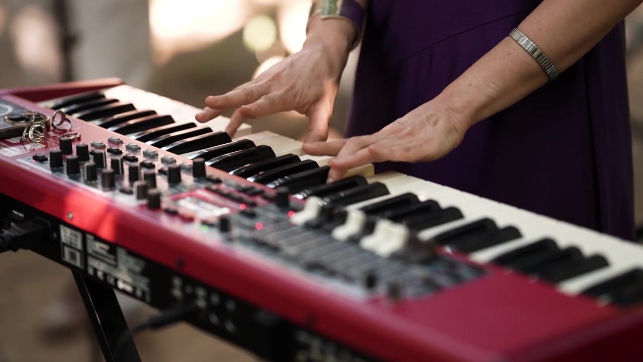 Mani del tastierista su un pianoforte da palco rosso con manopole per i drawbar e due tastiere ad un evento dal vivo