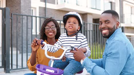 Porträtaufnahme-Einer-Jungen-Afroamerikanischen-Glücklichen-Familie-Mit-Einem-Kleinen-Süßen-Mädchen-Auf-Dem-Fahrrad,-Das-In-Die-Kamera-Im-Freien-Lächelt