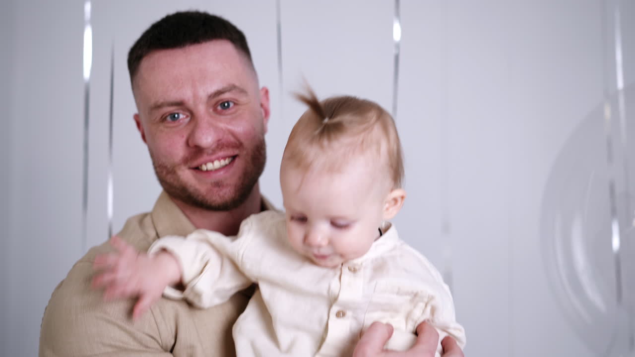 Lovely active one-year-old toddler in his dad's hands. Father touches the big balloon and kid looks with interest. Studio footage.
