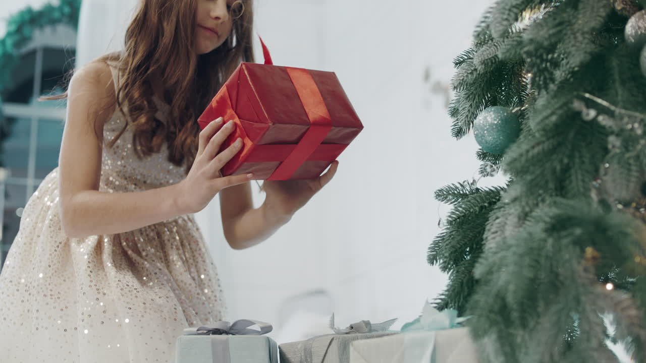 현대 아파트의 크리스마스 트리 근처에서 선물 상자를 가져가는 행복한 소녀.