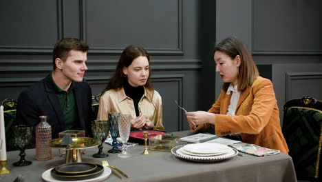 asian woman talking with a couple sitting at a table