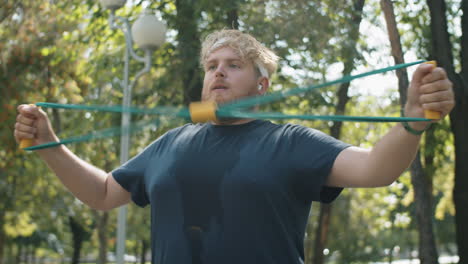 overweight man exercising with chest expander in park