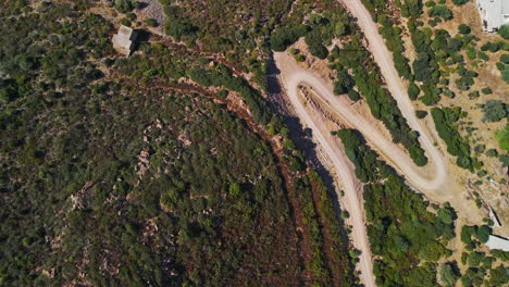 vista de pájaro del camino de tierra entre la vegetación mediterránea del campo en cerdeña, italia - drone aéreo disparado en cámara lenta