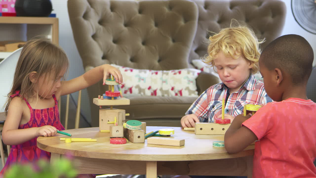 Alunos da Escola Montessori trabalhando na carteira com um conjunto de construção de madeira.