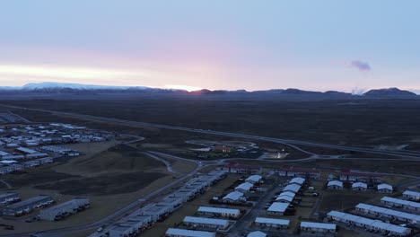 Sun-daybreak-above-horizon-at-Njardvik-town-in-Iceland,-residential-buildings,-aerial