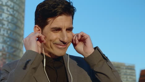 businessman putting earphones at street. employee listening music in earbuds