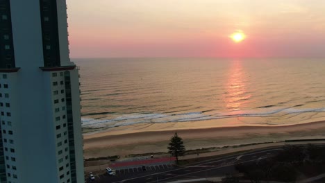 Rosafarbener,-Violetter-Sonnenaufgang-über-Dem-Meer,-Schwenk-Nach-Rechts-Mit-Wohnungen-Im-Vordergrund