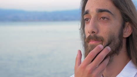 Man-with-long-hair-and-beard-on-sea-background