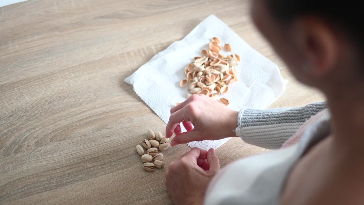 Young woman eating pistachios at home