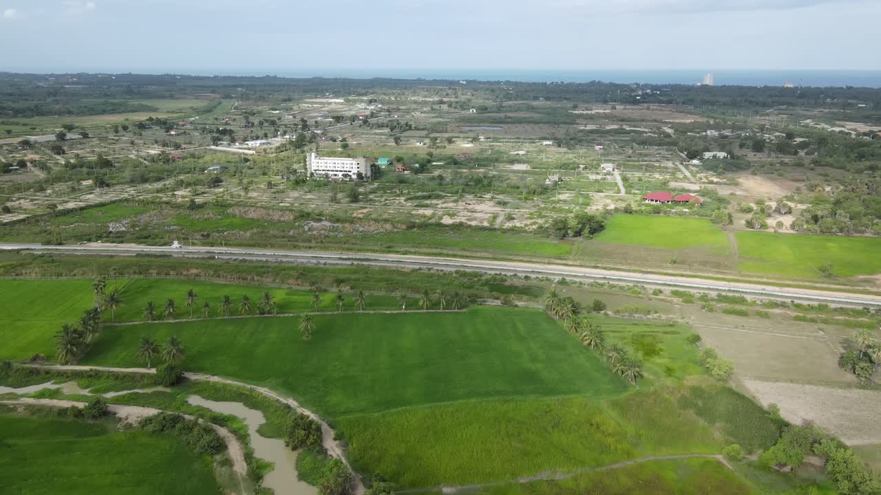 ภาพโดลลี่มุมสูงเหนือทุ่งนาและเส้นทางรถไฟในชะอำ ประเทศไทย