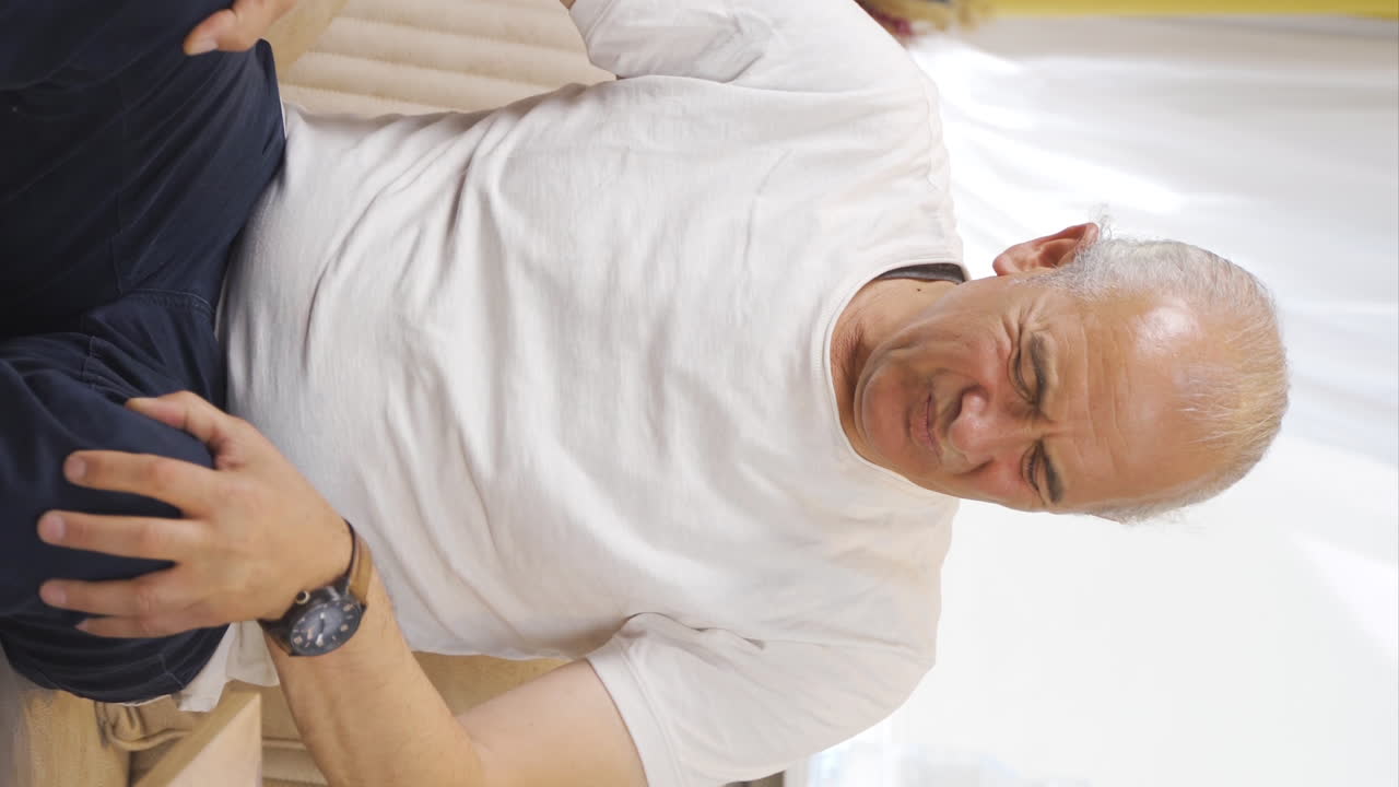 Vertical video of Old man experiencing pain in bones.