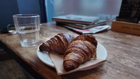 dos croissants y una mano masculina con anillo de boda vertiendo refresco en un vaso